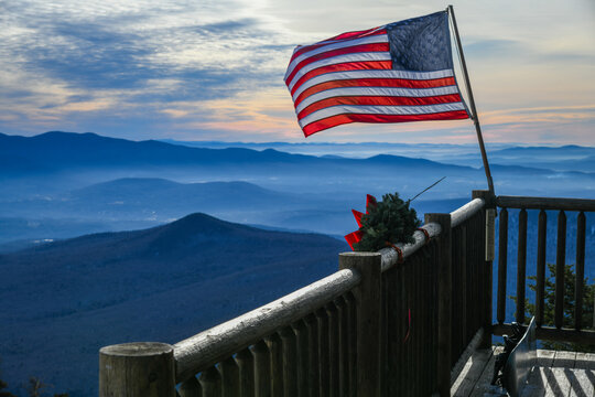American flag waiving at the ski patrol house on the beautiful winter day at the Stowe Mountain Ski Resort, Vermont. Top view with mountains silhouette on the background.