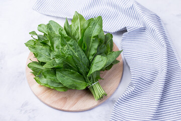 A bunch of fresh sorrel leaves on a light background with a napkin. Healthy greens for a healthy...