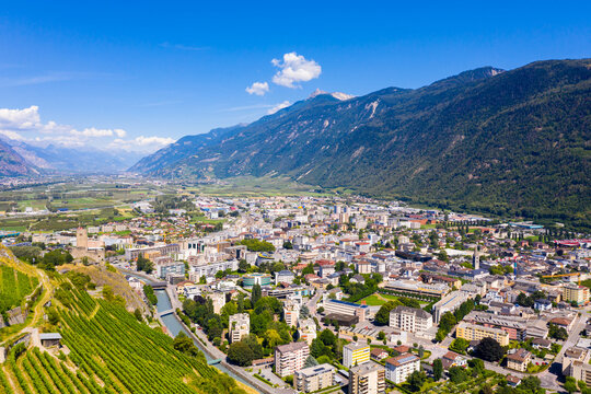 Summer view from drone of Martigny town in green valley on banks of Rhone river surrounded by Alps, Switzerland.