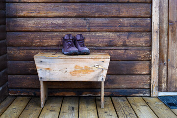 Closeup of leather hiking boots on a wood bench outside on the deck of a vacation cabin, ready for adventure
