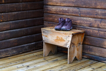 Closeup of leather hiking boots on a wood bench outside on the deck of a vacation cabin, ready for adventure
