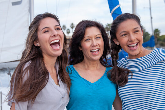 Portrait of happy mother with daughters standing by sailboat