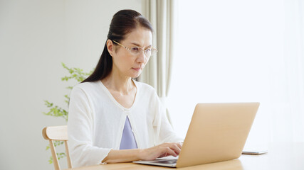 パソコンを使う老眼のシニア女性.