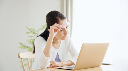 パソコンを使う老眼のシニア女性.