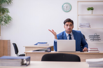Fototapeta premium Young male employee being unhappy with excessive work