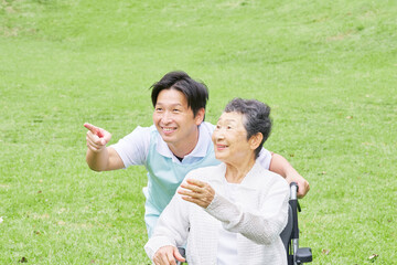 介護士と車椅子に乗る高齢者　屋外