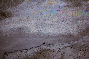 Gas stain on wet asphalt caused by a leak under a car or truck, abstract background