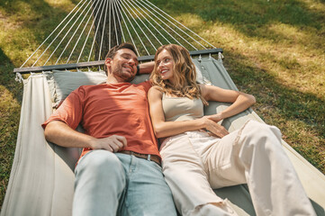 A man and a woman lying in a hammock and feeling relaxed