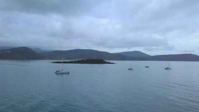 Drone flying on an overcast day towards a small Island off the coast of Airlie Beach, Shute harbour, North Queensland