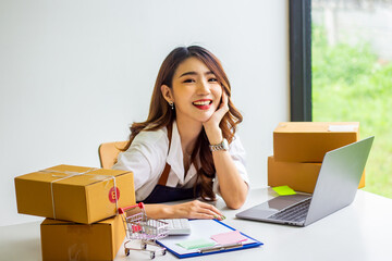 An online business owner checks the name and address of a customer ordering a company product, Cropped photo of a woman checking and writing the name on a parcel for delivery at an online sale office.