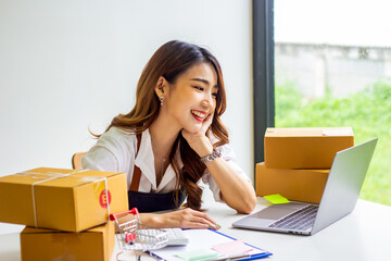 An online business owner checks the name and address of a customer ordering a company product, Cropped photo of a woman checking and writing the name on a parcel for delivery at an online sale office.