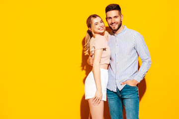 Obraz premium Sexy smiling beautiful woman and her handsome boyfriend. Happy cheerful family having tender moments near yellow wall in studio.Pure cheerful models hugging.Embracing each other