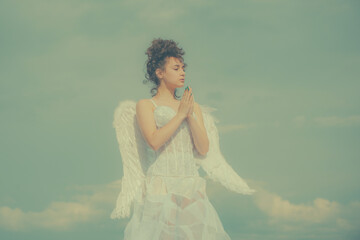 Fototapeta na wymiar Valentines angel teen praying. Angel teen in heaven. Teenage angel girl with wings, copy space on sky.