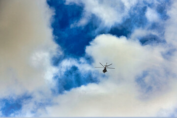 Flying helicopter on the background of clouds and blue sky