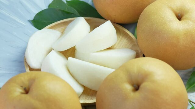 Snow pear fruit in wooden basket, Fresh Nashi pear or Korean pear fruit in the basket over green natural Blur background.