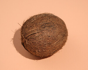 Ripe coconut brown color lies on table with a shadow. Idea healthy food and exotic holidays.