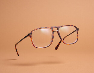 Horn-rimmed glasses retro-style on pastel beige background. Levitation fashion accessory.