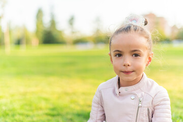 A little girl sitting on grass in a park