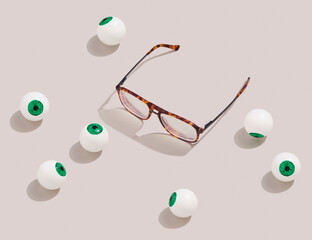Horn-rimmed glasses and eyeballs lie on pastel surface. Idea retro futurism and ridiculous...