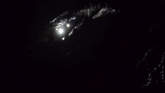 Cameraman films speleothems in black darkness of underground cave