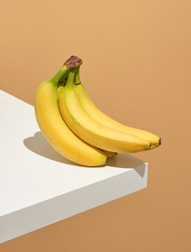 Bunch of delicious ripe yellow bananas on the corner of white table. Idea proper nutrition and summer.