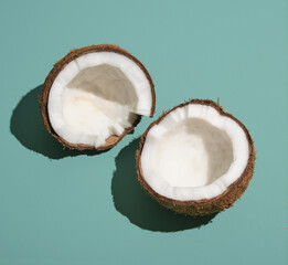 Two halves of coconut lies on table. Minimalistic summer exotic composition, rest and party.