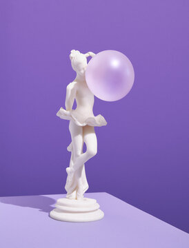 Statuette of ballerina stand with inflated bubble gum ball. Unusual approach to art, freedom creativity.
