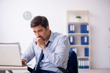 Naklejka premium Young male employee and too much work in the office