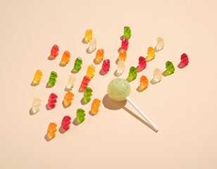 Sweet lollipop on stick and many bright tasty jelly bears. Sunny idea of taste, summer, vivid impressions.