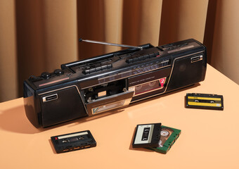 Obraz premium Retro cassette tape recorder and several audio cassettes. Beige pastel textile background. Scene of recreation, hobbies and light mood.