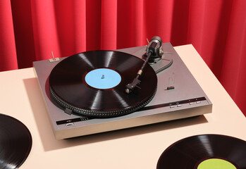 Composition with retro vinyl record player. Red textile background. Aesthetics of vintage parties and relaxing with friends.
