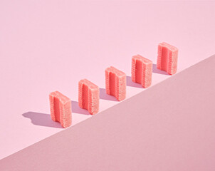 Sweet pink chewing gums stands in a row on the edge of table. Idea of taste, youth and positive...