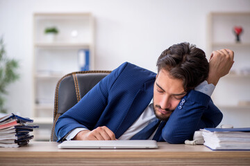 Young male employee extremely tired in the office