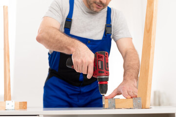 Cropped Shot Of Professional Carpenter Using Drill Assembling Table Indoor