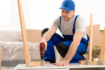 Handyman Assembling Wooden Table With Electric Drill Indoor