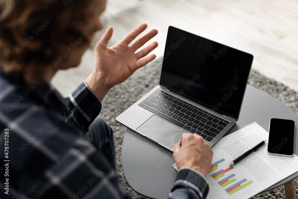 Poster man making video call on laptop with blank screen, back-view