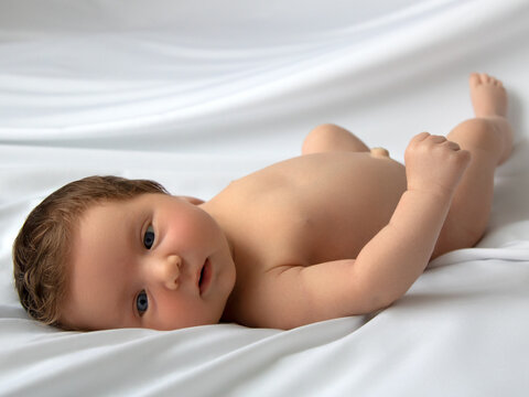 Newborn baby in a wrap on white blanket. Beautiful portrait of little child girl 7 days, one week old. Baby lying on back on white background