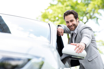 Attractive satisfied european man in suit touching new transport in auto store