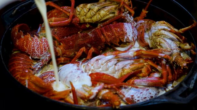 Adding fresh cream into seafood pot with crayfish on top; close shot