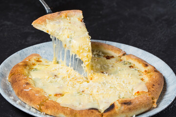 Tasty take slice of pizza with cheese. Appetizing separate piece of round pizza stretching melted cheese.