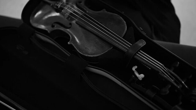 Musician packing violin into special case for transporting