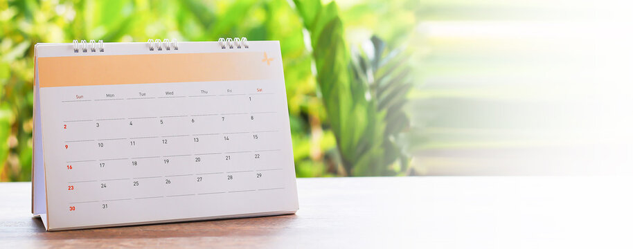 White desk calendar on dark wooden table, planning concept.	
