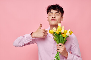 portrait of a young man Bouquet of yellow flowers romance posing fashion pink background unaltered