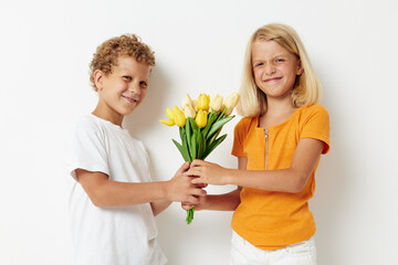 Fototapeta na wymiar picture of positive boy and girl holiday friendship with a gift Yellow flowers light background