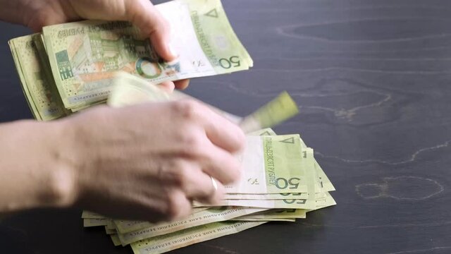 4k. Close-up view of counting stack of belarusian 50 ruble paper money. Hands hold and count a lot of cash. Saving. National currency of Belarus. Credit liabilities. Profit. Big debt. Taxes payment.