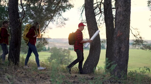 Family tourism. Group of people with map hiking in forest. People with backpacks in forest park. Hiking is healthy lifestyle. Group of ice is walking with map in forest park. Family tourism concept