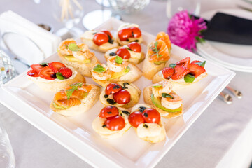 Bruschetta with tomatoes, mozzarella cheese and basil on a cutting board. Traditional italian appetizer or snack, antipasto. Caprese salad bruschetta. Top view with copy space.