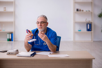 Old male doctor cardiologist working in the clinic