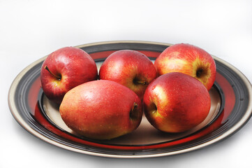 red oblong apples on a plate with a red border