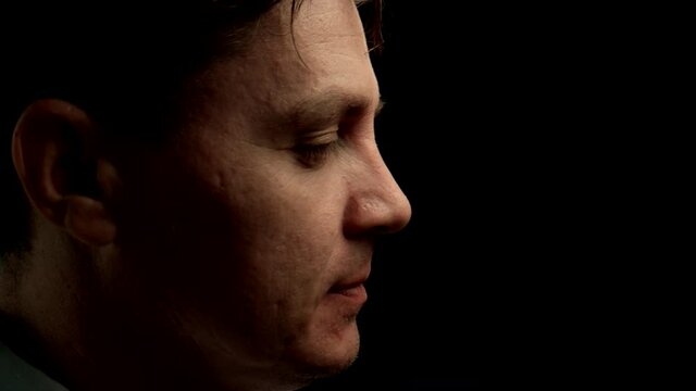 CLOSE UP: Young adult Man In Glasses Miming Are Changing Facial Expressions on a black background
